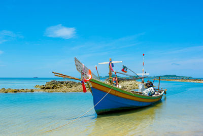 Boats moored on sea against blue sky