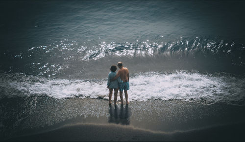 High angle view of couple standing on shore at beach