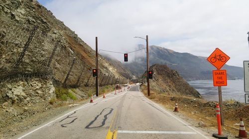 Empty road by mountains against sky