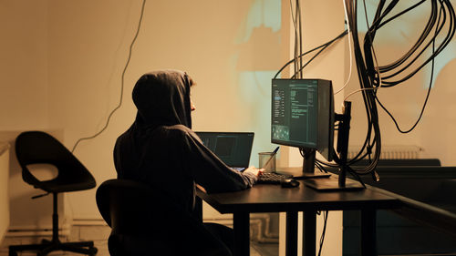 Rear view of woman using laptop at table