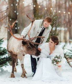 Young couple on snow covered tree during winter