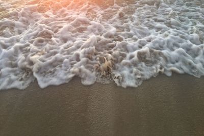 Close-up of sea waves on sand at beach