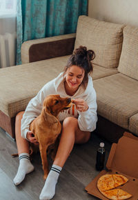 Young woman with dog sitting on sofa