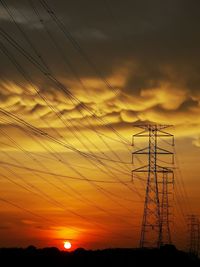 Low angle view of silhouette electricity pylon against sky during sunset