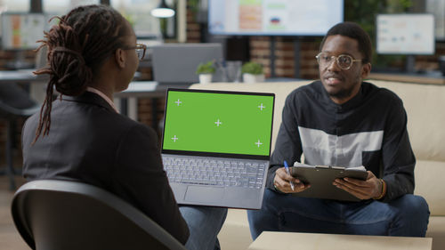 Businesswoman with colleague discussing over laptop