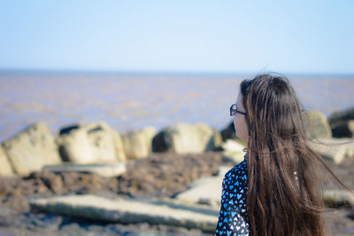 Girl looking at sea against sky