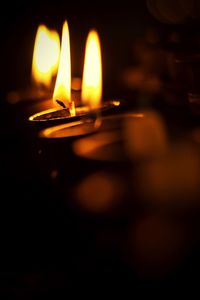 Close-up of lit candle in dark room