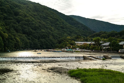 Scenic view of river by buildings against sky