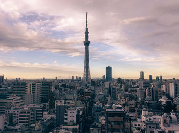 Aerial view of buildings in city against cloudy sky