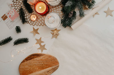 Christmas table decor, a roll of baking paper, burning white and red candles, wooden cutting board