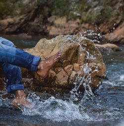 Low section of man splashing water in river