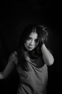 Portrait of beautiful young woman against black background