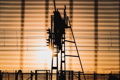 Silhouette electricity pylon against sky during sunset
