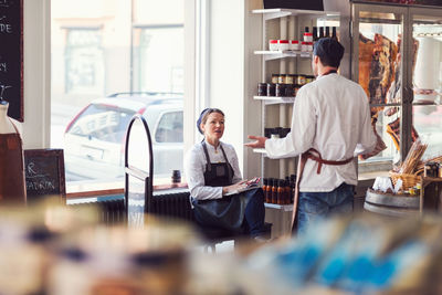 Male and female colleagues discussing in grocery store