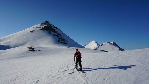 Rear view of person skiing on snowcapped mountain against clear sky