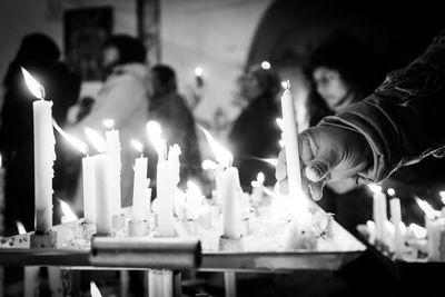Cropped hand holding lit candle at altar in church