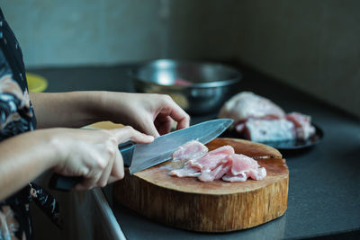 Midsection of woman cutting fish on wood