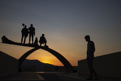 Silhouette people against orange sky