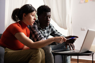 Side view of woman using digital tablet while sitting at home