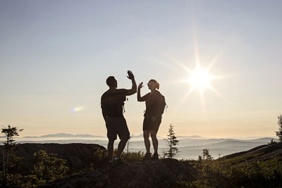 Two hikers high five and celebrate reaching summit of mountain, maine