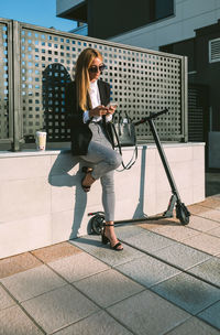 Woman using mobile phone while sitting on tiled floor