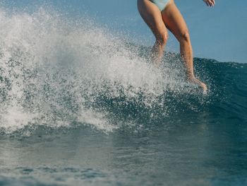 Low section of woman splashing water in sea