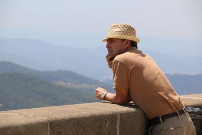 Side view of man looking at mountains against sky during sunny day