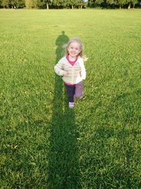 Portrait of happy girl standing on grassy field