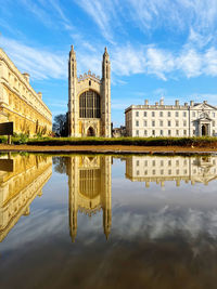 Sunlit kings college chapel cambridge and its reflection in a puddle