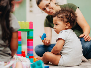 Cute boy playing with toy sitting with mother at home