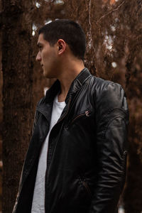 Side view of young man looking away in forest