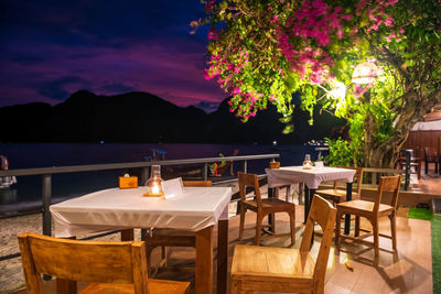 Empty chairs and tables and table and lounge chair and flowers on beach