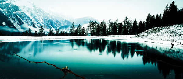 Scenic view of lake by snowcapped mountains against sky