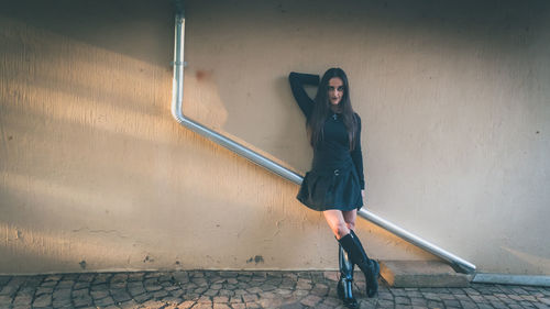 Portrait of woman standing against wall