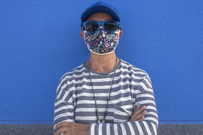 Woman wearing sunglasses standing against blue wall