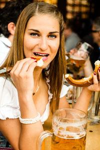 Portrait of young woman having pretzel during oktoberfest