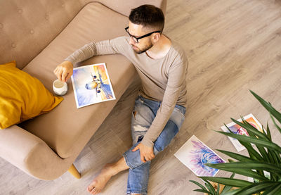 The artist is sitting on the floor with a cup of coffee.  real emotions lifestyle.