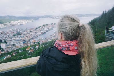 Rear view of woman looking at cityscape against sky