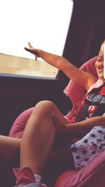 Midsection of woman sitting by window at home