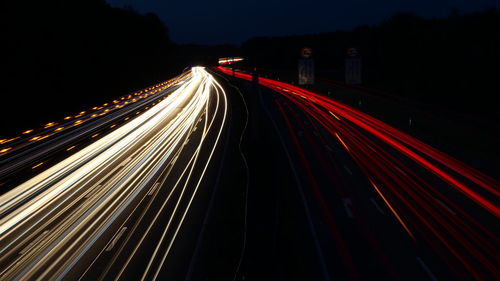 Light trails on road against sky at night