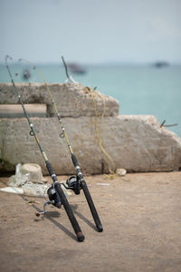 Fishing rods at beach against sky