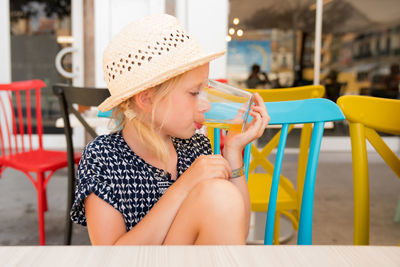 Girl looking away while sitting on table