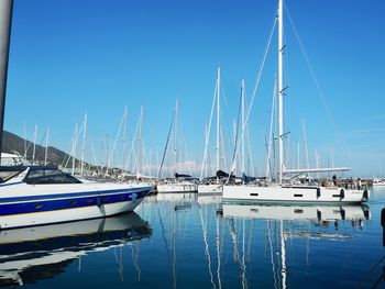 Sailboats moored at harbor against clear blue sky