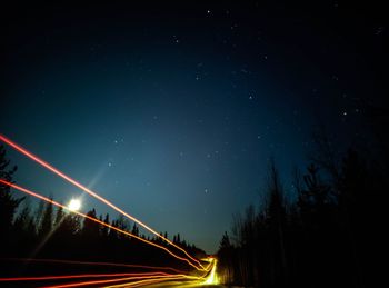 Low angle view of light trails against sky at night