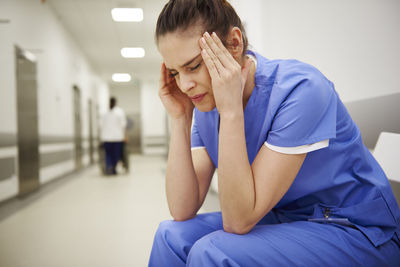 Doctor with head in hands sitting at hospital