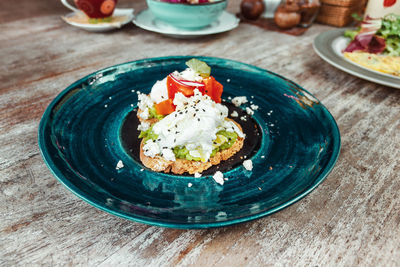 Avocado toast with scrambled eggs on the blue plate on the wood table. healthy food for breakfast