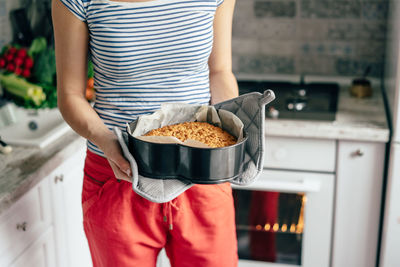 Midsection of woman holding ice cream at home