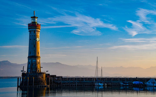 Lighthouse by sea against sky during sunset