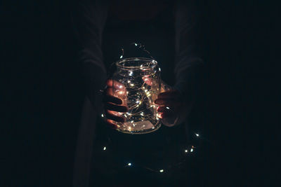 Person holding glass of illuminated candles