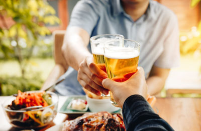 Midsection of woman holding beer glass on table